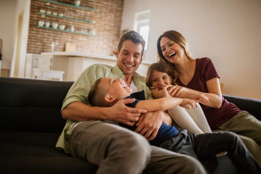YoungFamilyPlayingOnTheCouchTogetherInTheLiving | Red Penny Realty Family enjoying their new Phoenix home together